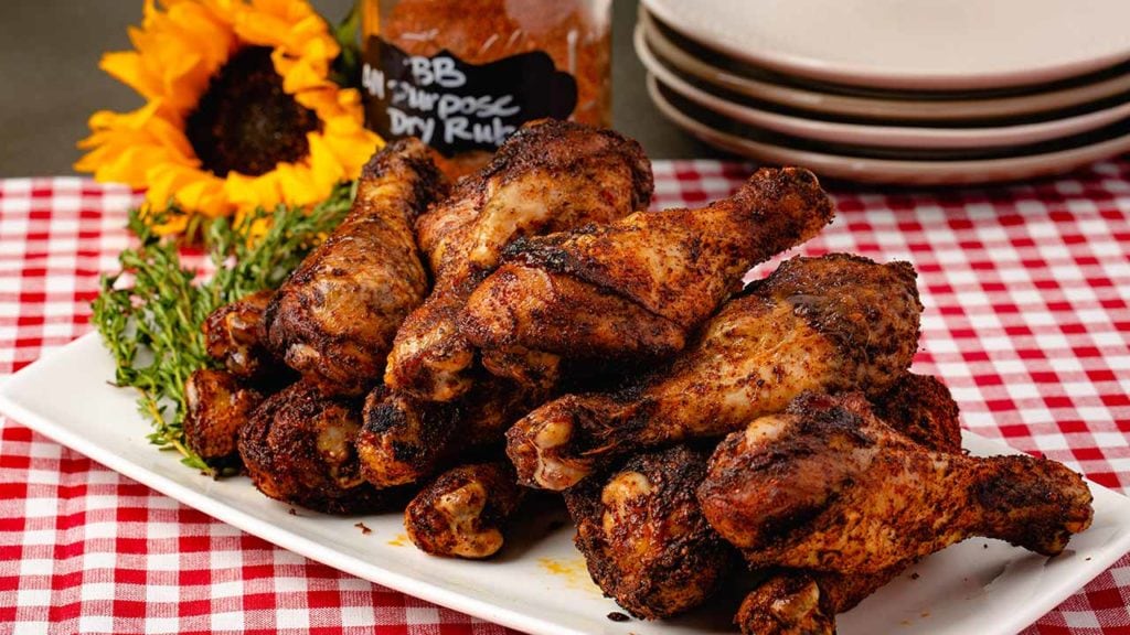 Dry-rubbed chicken drumsticks on a picnic table