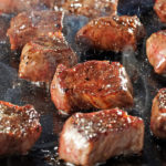 steak tips cooking on cast-iron