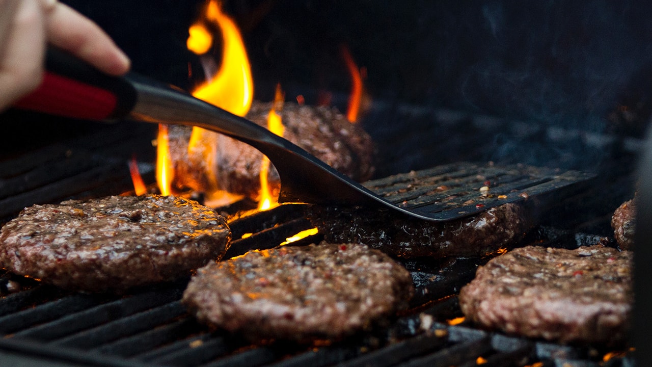 Chef making burger. Beef or pork meat barbecue burgers for hamburger  prepared grilled on bbq fire flame grill. Close-up shot of chef's hands  turn the chop on the grill Stock Photo