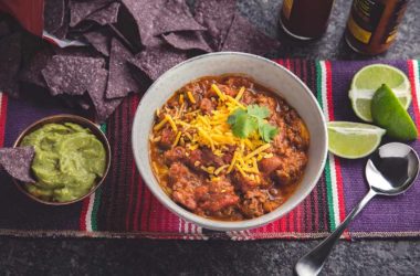 beef and kidney bean chili with guacamole, limes, and tortilla chips