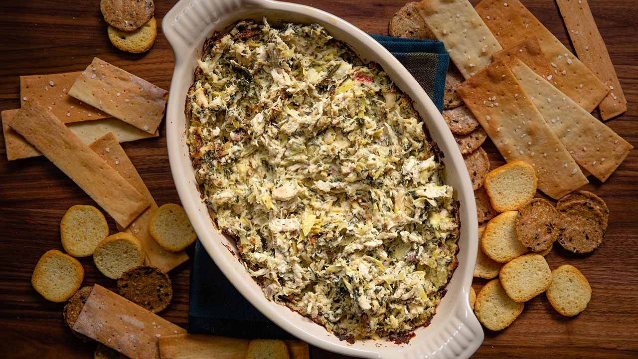 Bowl of tuscan chicken dip surrounded by crackers