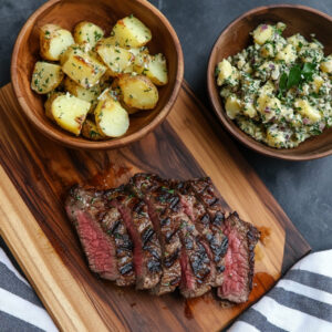 NY Strip Steak with Herby Potato Salad on a chopping board and bowl