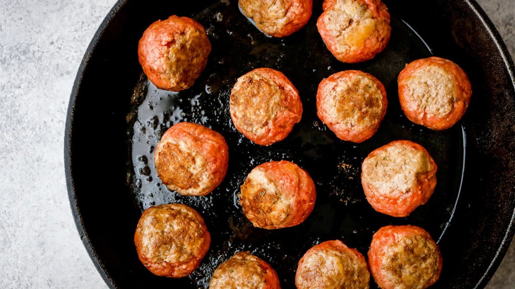 Cooking frozen meatballs in a cast iron skillet.