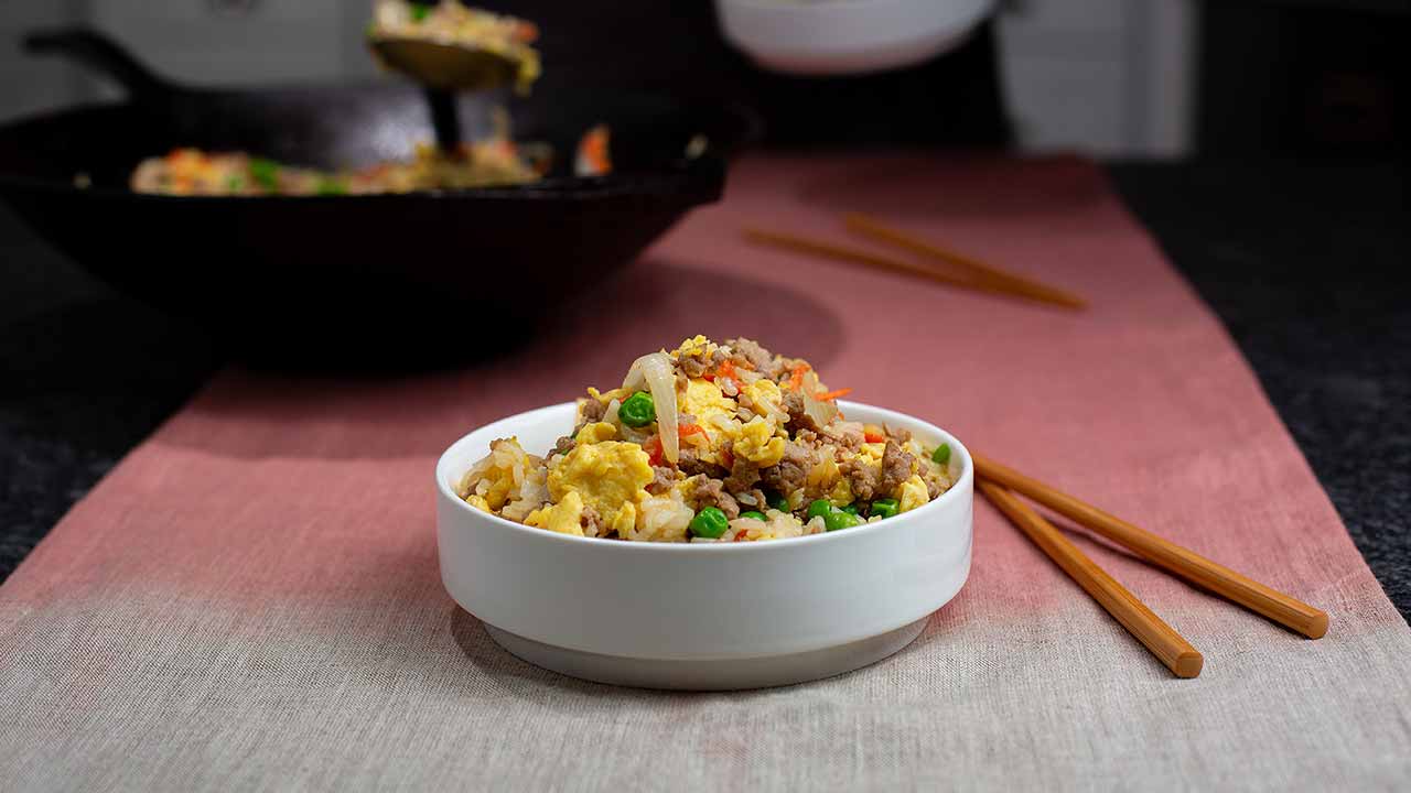 bowl of ground pork fried rice on a table with chopsticks