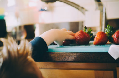 kids grabbing strawberries in kitchen