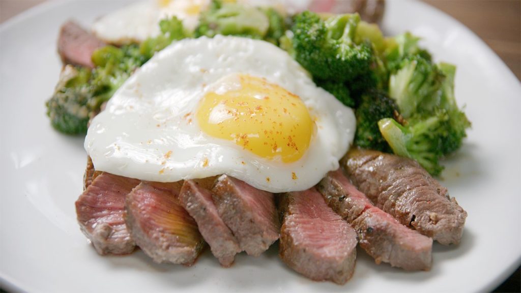 Sliced sirloin steak topped with a fried egg.