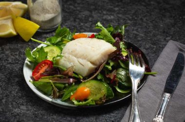 baked cod filet on a bed of greens and vegetables