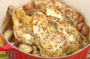 baked chicken in red dutch oven with potatoes