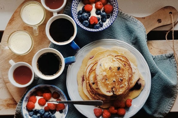 pancake breakfast board with yogurt, berries, and coffee