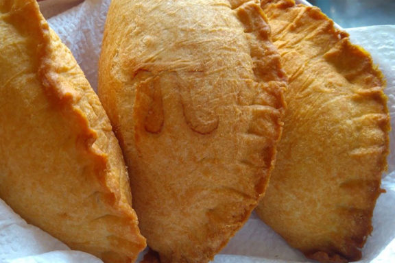 Three meat hand pies on a paper towel with a pi symbol on one of them