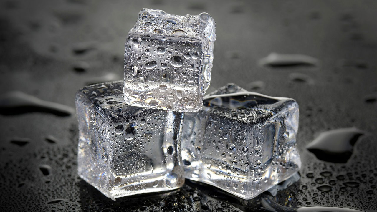three ice cubes melting onto a table