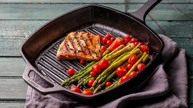 Sockeye salmon filet, tomatoes, and asparagus in a grill pan