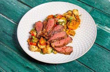 Steak surrounded by a bruschetta salad on a plate