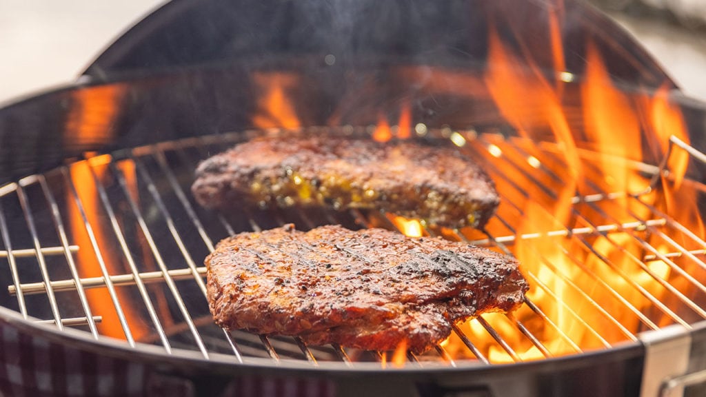 steaks on grill with flames
