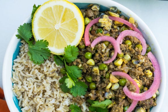 picadillo criollo in a bowl with a lemon wedge