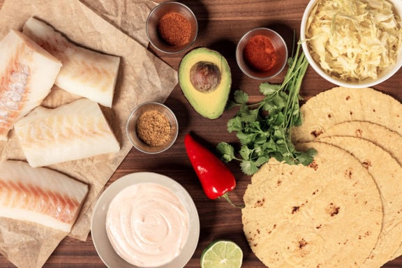 spices, avocado, cheese, tortillas, and defrosted cod laid out for tacos