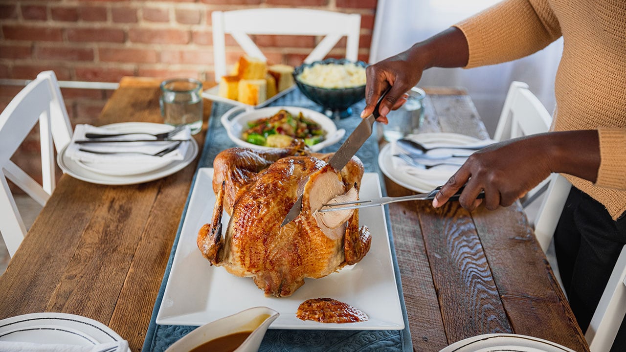person carving a roasted turkey at the dinner table