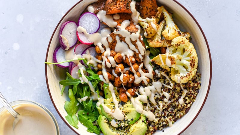 grain bowl with vegetables like radishes, chickpeas, greens, avocado, and cauliflower