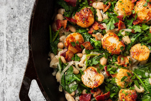 scallops spinach beans and bacon in a skillet
