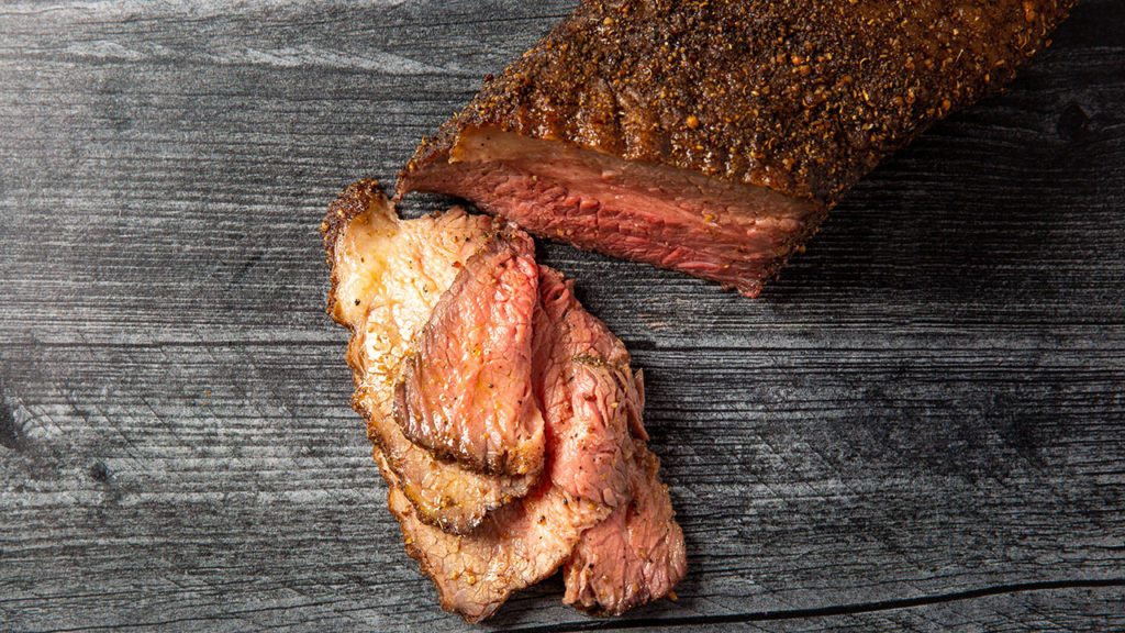A cooked slab of brisket sliced thinly.