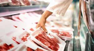 Closeup side view of unrecognizable woman choosing meat at local supermarket.